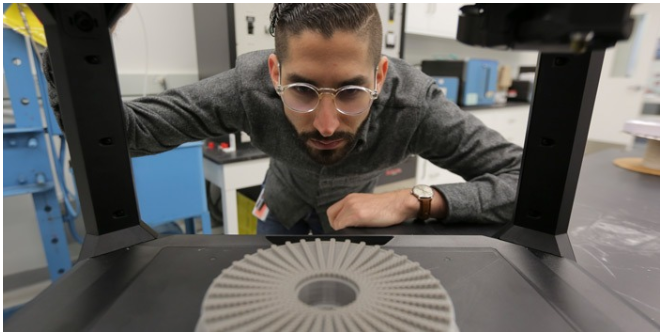 Research engineer Guy Chriqui inspects a freshly printed part.